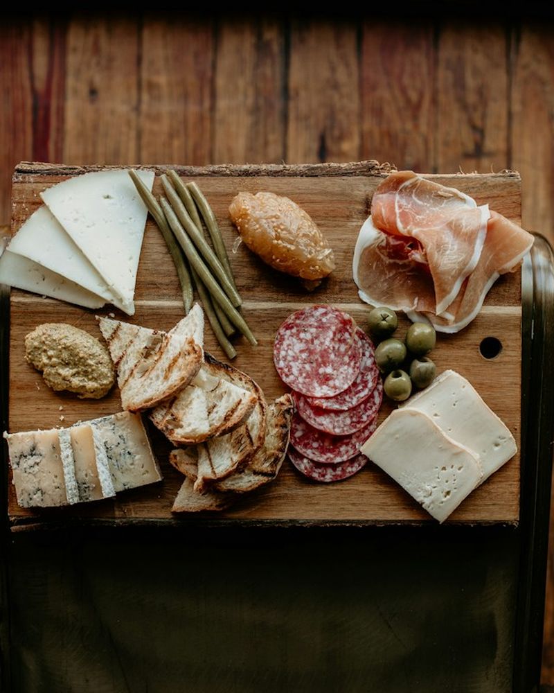 Board of sliced cheeses, salami and cured ham