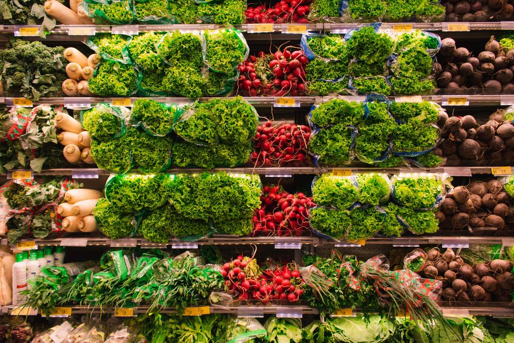 Crates of tomatoes, radishes and leafy greens on a market display